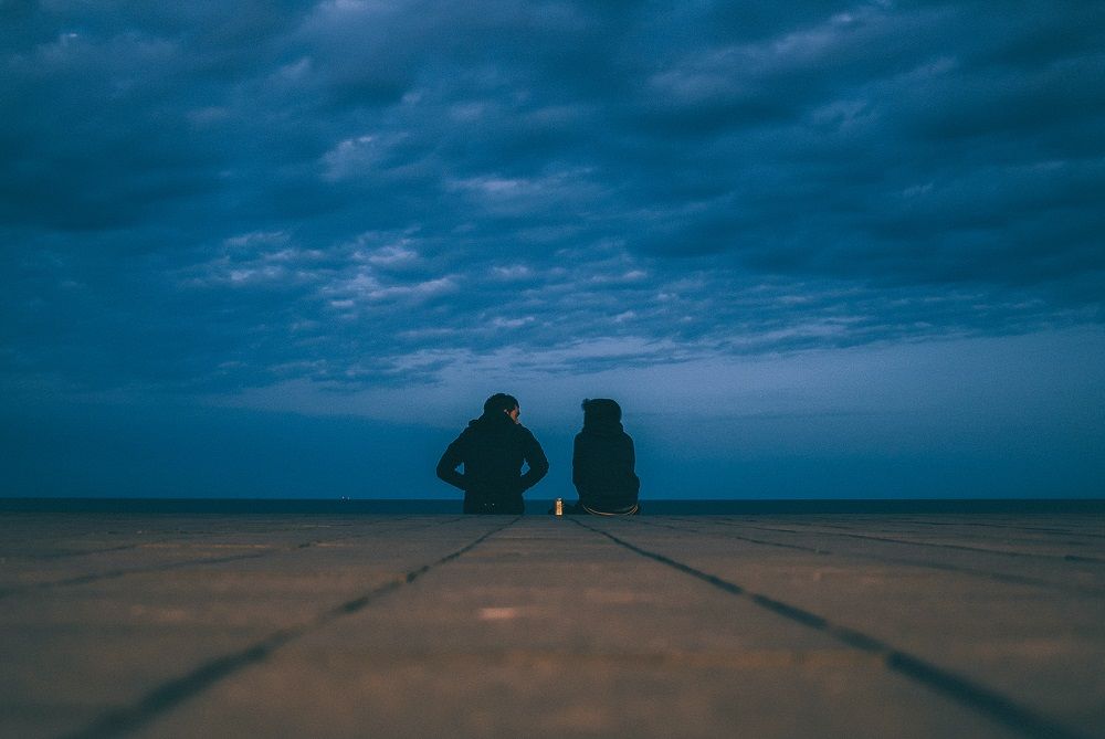 Couple sitting by the water talking about their relationship problems